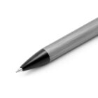 A close-up of a metal ballpoint pen with a textured body and a black tip. The pen is angled from the lower left to the upper right of the image against a white background.
