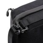 Close-up of a black crossbody bag featuring a textured fabric. The image highlights a sturdy zipper and an adjustable strap with a secure metal clasp. The bags material appears to be durable, suitable for everyday use.