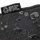 Close-up of a black textured fabric with water droplets on the surface. A tag reads Made from recycled PET bottles with a recycling symbol.