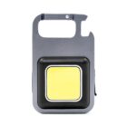 A compact, rectangular grey and black keychain flashlight with a bottle opener feature. It has a bright yellow light panel in the center and a loop for attaching to keys or bags.