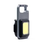 A close-up of a compact, rectangular keychain flashlight with a metallic frame and a large, flat yellow light panel. The design is sleek and minimalistic.