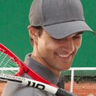 Smiling man in a gray cap holding a tennis racket on a court.