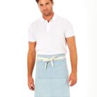 A person wearing a white polo shirt and a light blue apron stands against a plain white background. The apron has a front pocket and is tied with a beige strap. The individual has short brown hair and a slight smile.