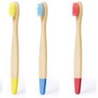 Five bamboo toothbrushes with different colored bristles and matching bottom handles: white, yellow, blue, red, and green, all arranged vertically against a white background.