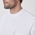 Man in a white medical uniform with a pen in the chest pocket, looking to the left. The uniform has buttons near the shoulder and short sleeves. The background is plain white.