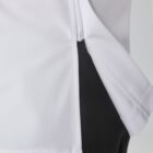 Close-up of a person wearing a white shirt with a zipper detail on the side seam. The shirt overlaps black pants, highlighting the contrasting colors and the garments design.