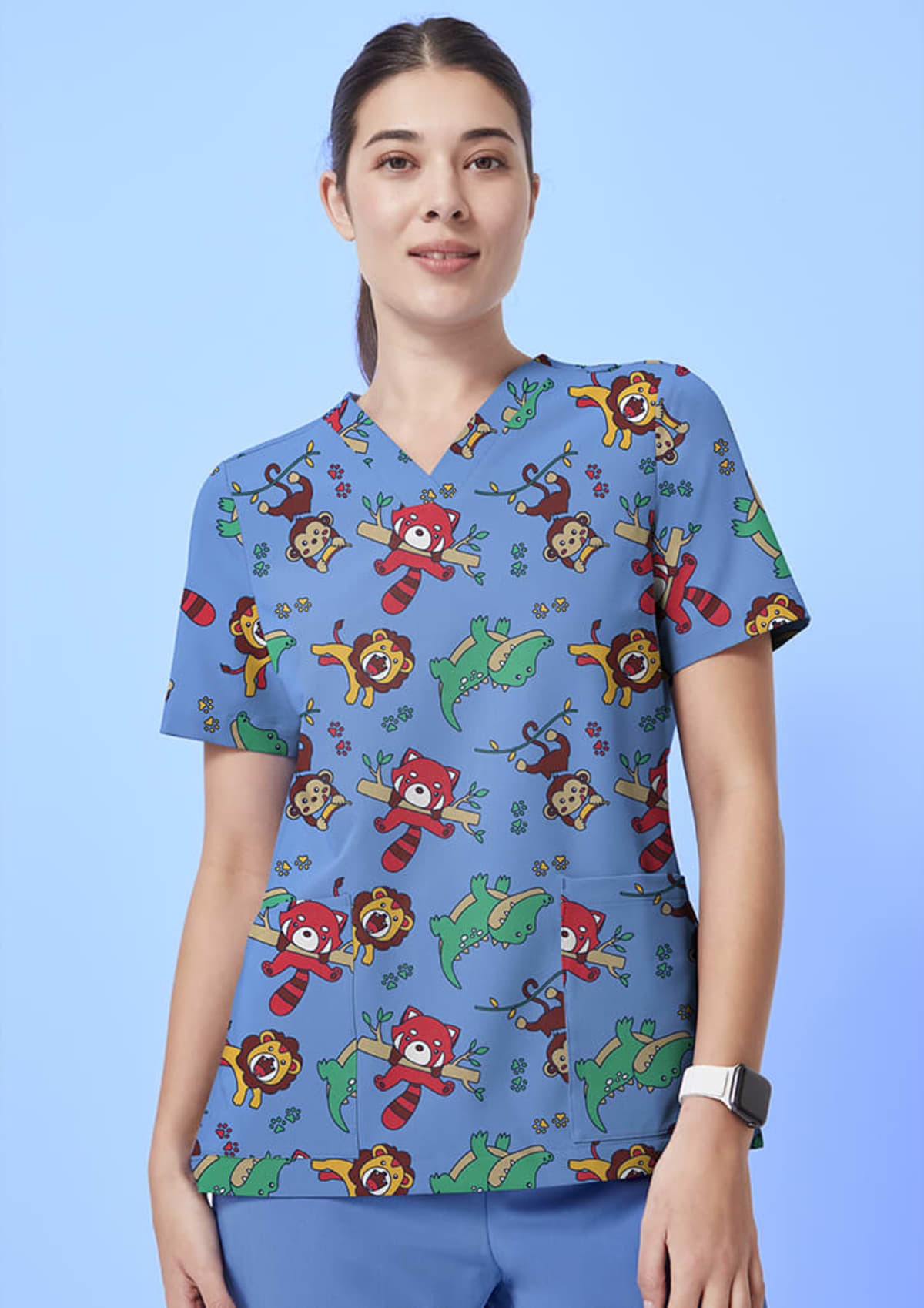 A person wearing scrubs with a playful pattern of colorful animals, including pandas, lions, and turtles, stands against a light blue background. They are smiling and have dark hair tied back.