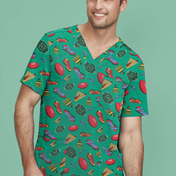 A man is smiling and wearing a green scrub top with a playful pattern of sports equipment, snacks, and shoes. The background is a solid light green color.