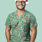 A smiling person wearing glasses is dressed in a festive green scrub top with holiday-themed prints. They are also wearing a reindeer antler headband with a Santa hat. The background is a solid mint green color.