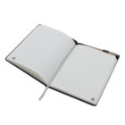 An open notebook with lined pages and a black cover. A pen is attached to the side of the notebook, and a gray ribbon bookmark is placed between the pages.