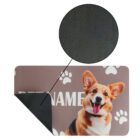 A pet food mat with a brown Corgi dog image, paw prints, and partially obscured text PET, with a close-up circle highlighting the non-slip black backing.