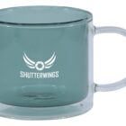 Clear glass mug with SHUTTERWINGS logo and stylized wings printed on the side.