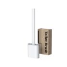 A sleek white toilet brush with a rectangular base stands upright next to a cardboard packaging box labeled Toilet Brush. The design is minimalist and modern.