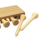 Close-up of a wooden block with multiple holes, holding several wooden pegs. Two pegs are placed on the surface in front of the block. The pegs have a cylindrical shape with one flat end and one pointed end.