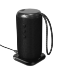 Black cylindrical Bluetooth speaker with control buttons, charging via a cable on a dock.