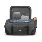 A gray and black duffel bag is open, displaying folded clothes and shoes inside. The inner mesh pocket holds smaller items. The bag has a zippered side pocket and a logo on the front.