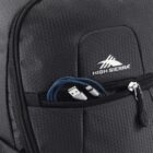 Close-up of a black High Sierra backpack featuring a hexagonal pattern. The front zipper pocket is slightly open, revealing a blue USB cable with both connectors visible. The brand logo is prominently displayed on the backpack.