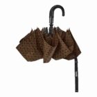 A folded, brown umbrella with a repeating black pattern. It has a curved black handle and a black strap with the word BOSS in white letters.