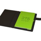 A black leather folder is open, revealing a lime green notebook inside. The notebook cover has 275 KENT embossed on it.