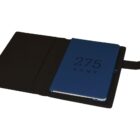 Black leather case with a blue notebook inside, displaying the text 275 KENT. The notebook is partially open, showing its dark cover and pages. The case has a flap with a loop closure.