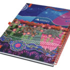 A colorful spiral-bound notebook with vibrant artwork featuring animals, plants, and celestial elements. The cover displays the logo of Cushman & Wakefield.