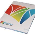 A spiral-bound white notebook with a colorful geometric design on the cover. It features the text SYDNEY Destination NSW in blue at the bottom left.