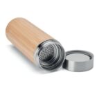 A stainless steel and bamboo thermos lies on its side with its cap removed, revealing a perforated metal infuser inside. The design combines natural bamboo with sleek metallic elements.
