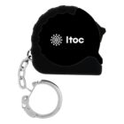 A black tape measure with a keychain attached. The side of the tape measure displays a logo with a circular dotted pattern and the word Itoc.