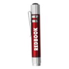 A red metal penlight with a silver clip. The word REDBOOK is printed vertically in white on its barrel. The penlight has a black button on top and silver accents at both ends.