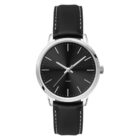 A simple analog watch with a black face and silver hour markers sits in a stainless steel case. It has a black leather strap with white stitching and a classic design.