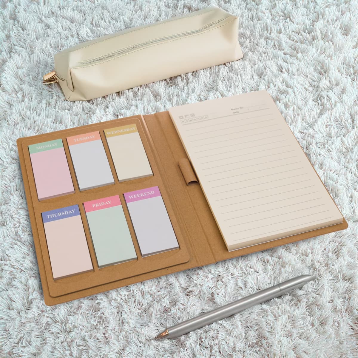 An open notebook with lined paper and colorful sticky notes labeled for each weekday. A beige pencil case and a silver pen are nearby, all placed on a textured white surface.