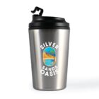 A silver stainless steel travel mug with a black lid. The mug has a logo featuring an illustrated desert scene with a sand dune, palm tree, and a blue body of water, surrounded by the text Silver Sands Oasis.