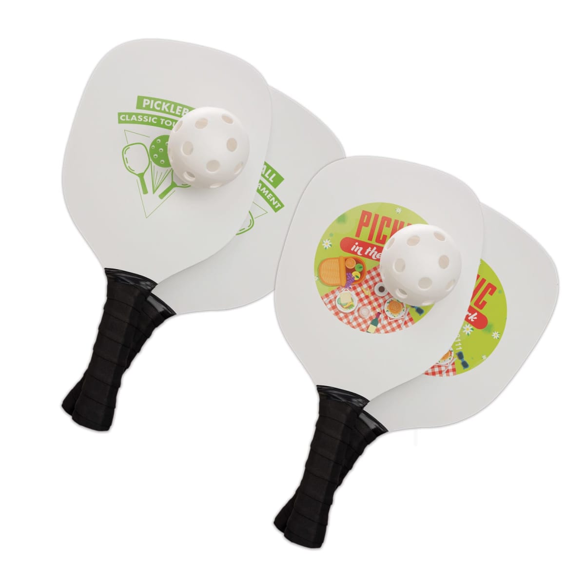 Two pickleball paddles with black handles and white faces displaying pickle-themed designs. Each paddle is paired with a white perforated pickleball. The designs feature pickles and playful text.