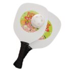 Two white pickleball paddles with black handles are crossed, featuring a colorful Picnic in the Park design. A white perforated pickleball rests on top.