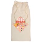 A beige drawstring bag with a Picnic in the Park design. The graphic includes a red checkered pattern with a picnic basket, utensils, and various foods on top.