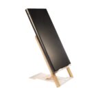 A slim black laptop positioned vertically on a wooden stand against a white background.
