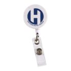 A retractable badge holder with a white circular top featuring a blue logo with the letter H and the text HAVANA HOTEL GROUP. Attached is a clear plastic strap with a metal snap for attaching a badge.
