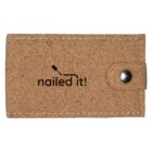 A rectangular cork wallet with a metal snap button. The text nailed it! is printed on it, with a graphic of a hammer above the letter i.
