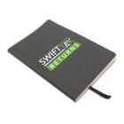 A closed black notebook with Swift Tax Returns printed on the cover in white and green text. A black ribbon bookmark is visible at the bottom. The notebook is angled slightly on a white background.