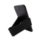 A black smartphone is propped up on a black stand with a triangular shape. The stand holds the phone securely at an angle, with its back facing the viewer. The set-up suggests hands-free usage or display.