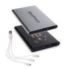 Two slim portable power banks, one silver with BlackMoon Interactive text and the other black with colorful graphics, are shown alongside a white multi-tip USB charging cable with micro USB, USB-C, and Lightning connectors.