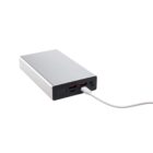 A silver power bank with a black end featuring three USB ports, one of which is connected to a white charging cable.