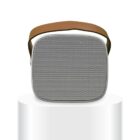 A portable wireless speaker with a perforated front grille and a brown carrying strap, placed on a sleek, glossy white podium against a plain white background.