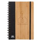 A spiral-bound notebook with a bamboo cover and a black elastic band. The cover features the Metro Estates logo with a house symbol. Theres an RPET stamp indicating recycled materials.