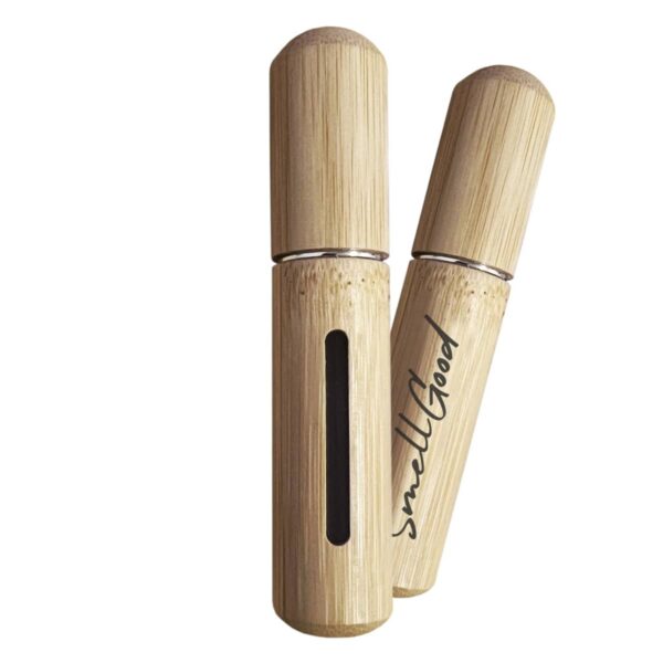 Two bamboo toothbrush holders, one standing upright and the other slightly tilted, with the word smellgood printed on the side. The upright holder has a vertical cutout revealing space inside. Both have rounded caps.