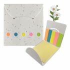 An open seed paper envelope with a floral design contains colorful sticky notes in blue, yellow, pink, orange, and green. A small daisy plant is inserted through the seam.