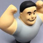 A rubber figurine of a person with a smiling face, black hair, and raised arms, wearing a light gray shirt. The figure appears to be showing off its muscles. The background is a plain gray surface.