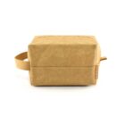 A tan rectangular toiletry bag with a handle on the side, displayed against a white background. The bag has a modern, minimalist design and appears to be made of durable fabric.