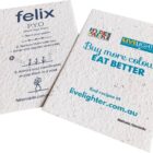 Two eco-friendly seed packets are displayed. The first features planting instructions for seeds with step-by-step guidance. The second promotes healthy eating with the slogan Buy more colour, EAT BETTER and includes a website link for recipes.