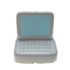 A simple, stylized toy computer with a light blue screen and a gray keyboard. The design is minimalist, with no visible detail on the keys or screen, resembling an old-fashioned desktop computer.